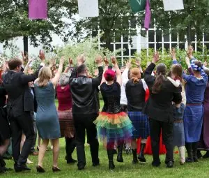 Verschiedene Menschen in festlicher Kleidung von Hinten bei einem Segenstanz für das Hochzeitspaar.